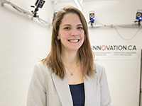 Dr. Angelica Lang is pictured in her lab, a white woman with shoulder length brown hair.